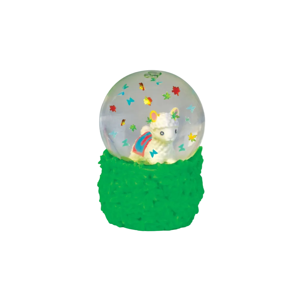A decorative snow globe figurine with a white llama or alpaca inside a clear globe, surrounded by small colorful star and butterfly decorations, set on a textured bright green base against a plain white background.