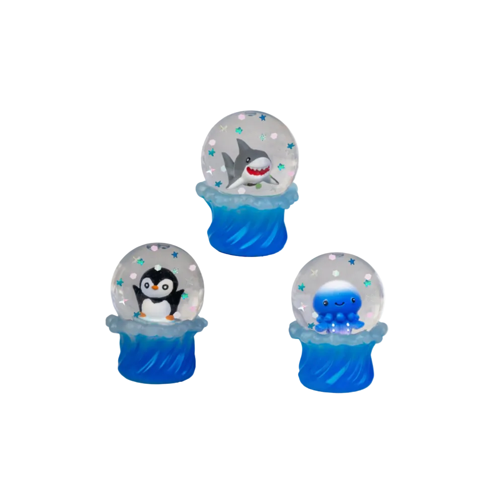Three small snow globe decorations on a plain white background, each with a blue wave-like base and a clear globe containing a different cartoon animal: a shark, a penguin, and a blue octopus, with small star and dot accents inside.
