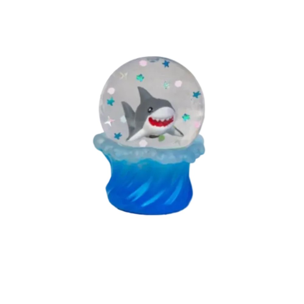 Three small snow globe-style figurines with blue wave bases on a white background. The globes contain different sea-themed characters: a gray shark with red teeth, a black-and-white penguin, and a blue octopus, with pastel star and dot confetti inside clear spheres.