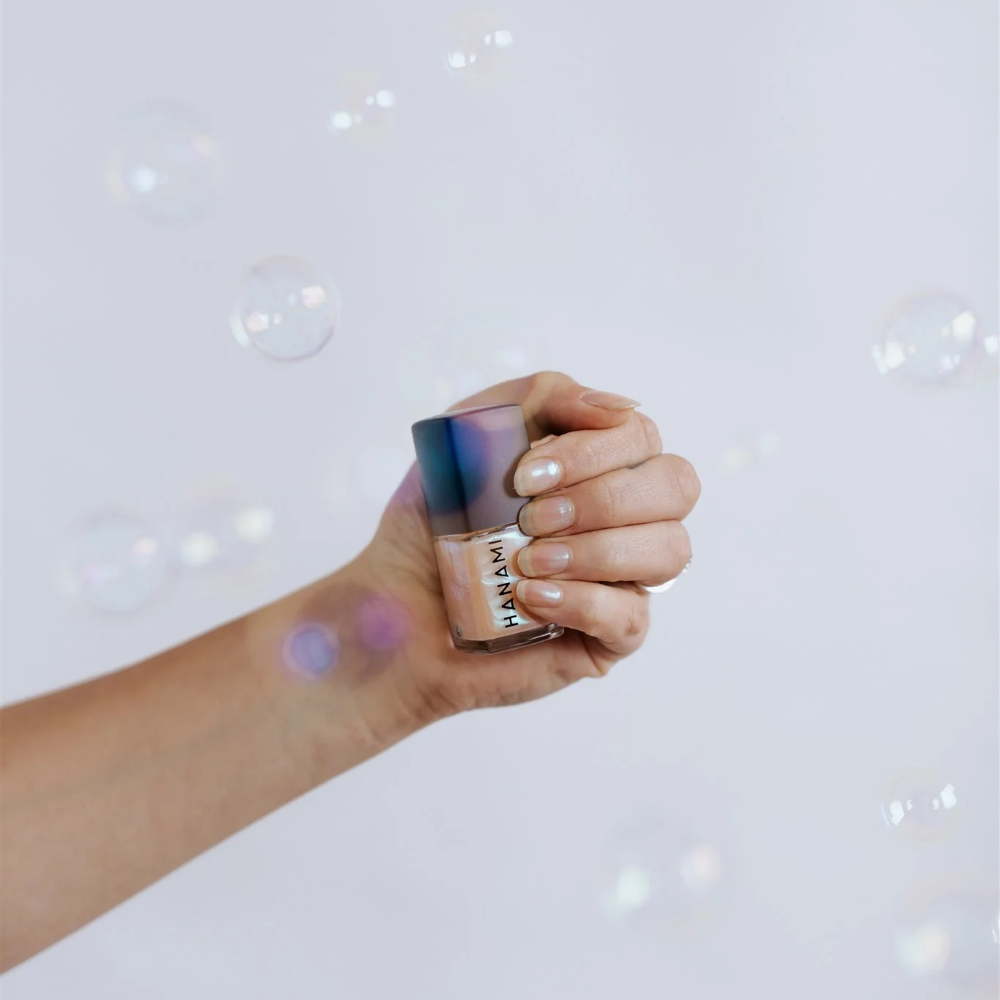 Hand holding a makeup product against a light background