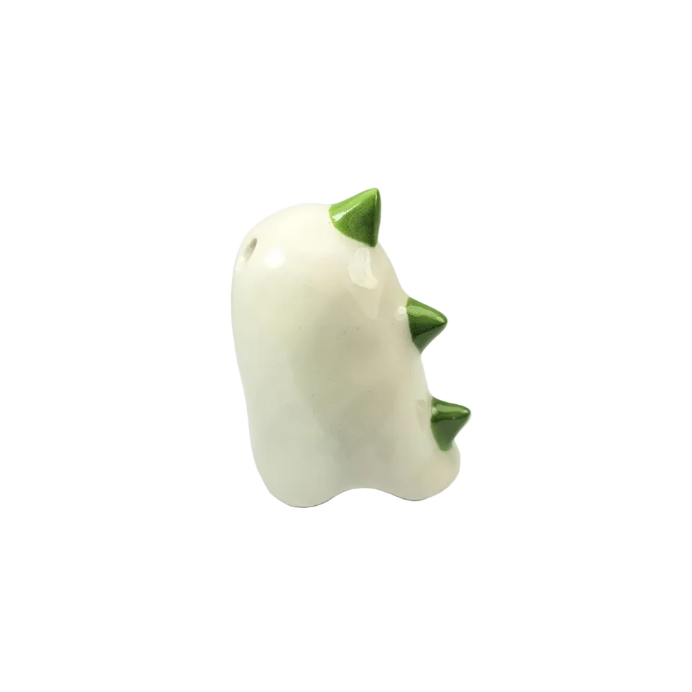 A ceramic ocarina-style instrument shown from the back, featuring a glossy off-white body with three green glazed spikes and a small hole near the top, photographed against a seamless light gray studio background.