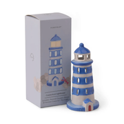 A blue and white lighthouse-shaped ceramic incense holder stands next to its light gray packaging box, which features an illustration of the lighthouse and the brand name Paddywax.