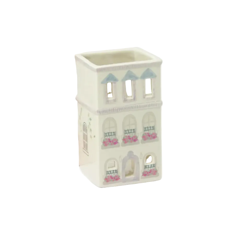 Paddywax Parisian Townhouse ceramic oil lamp and its pink packaging box, featuring a cream-colored house design with blue roofs and pink flower details.