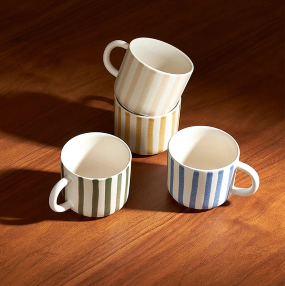 Four striped ceramic mugs on a wooden surface