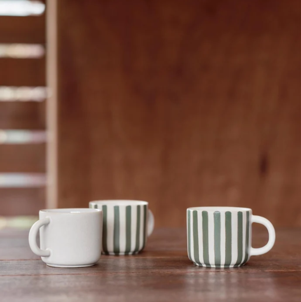 Three ceramic mugs with different patterns on a wooden surface.