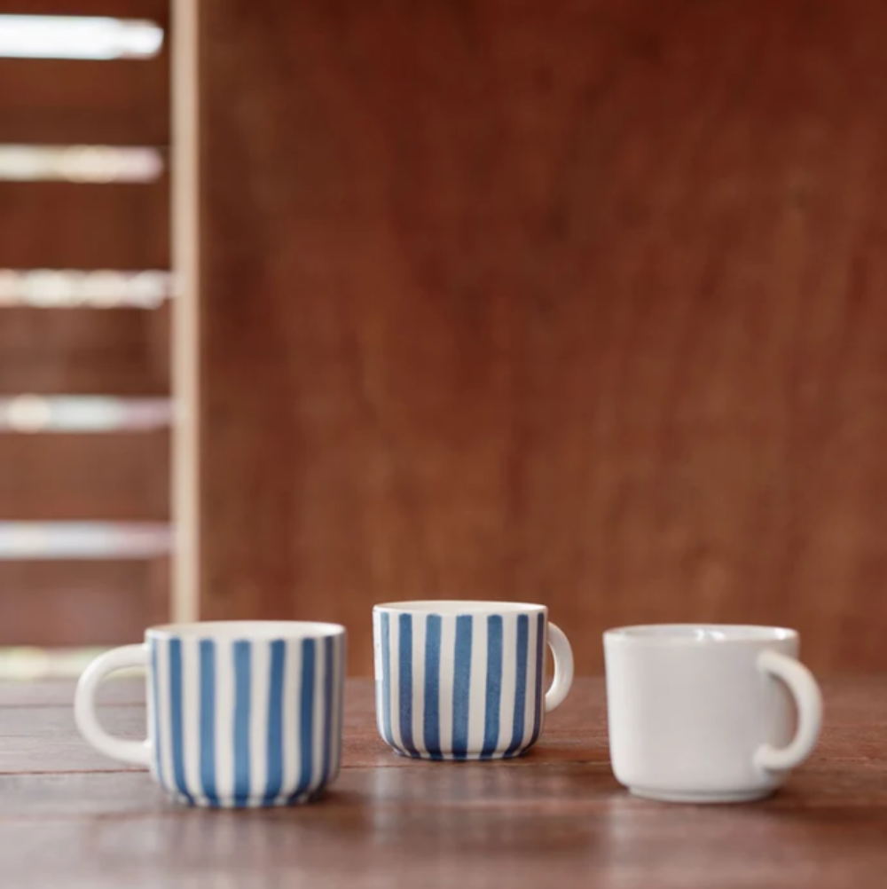 Three ceramic mugs with different designs on a wooden surface.