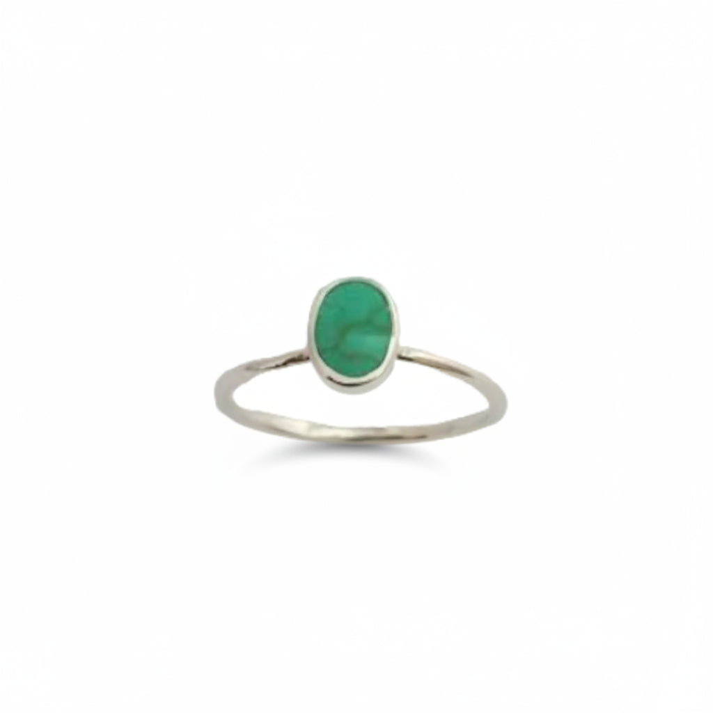 A silver ring featuring an oval green stone, photographed against a plain light gray background.
