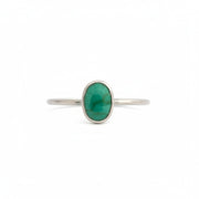 A delicate silver ring featuring an oval green stone, set against a plain white background.