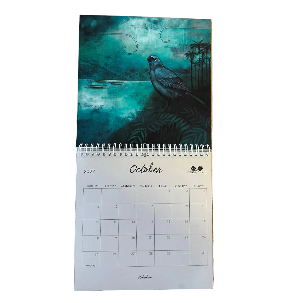 A spiral-bound wall calendar page from November 2027, featuring a teal-toned bird illustration on the cover, placed on a light wood surface.