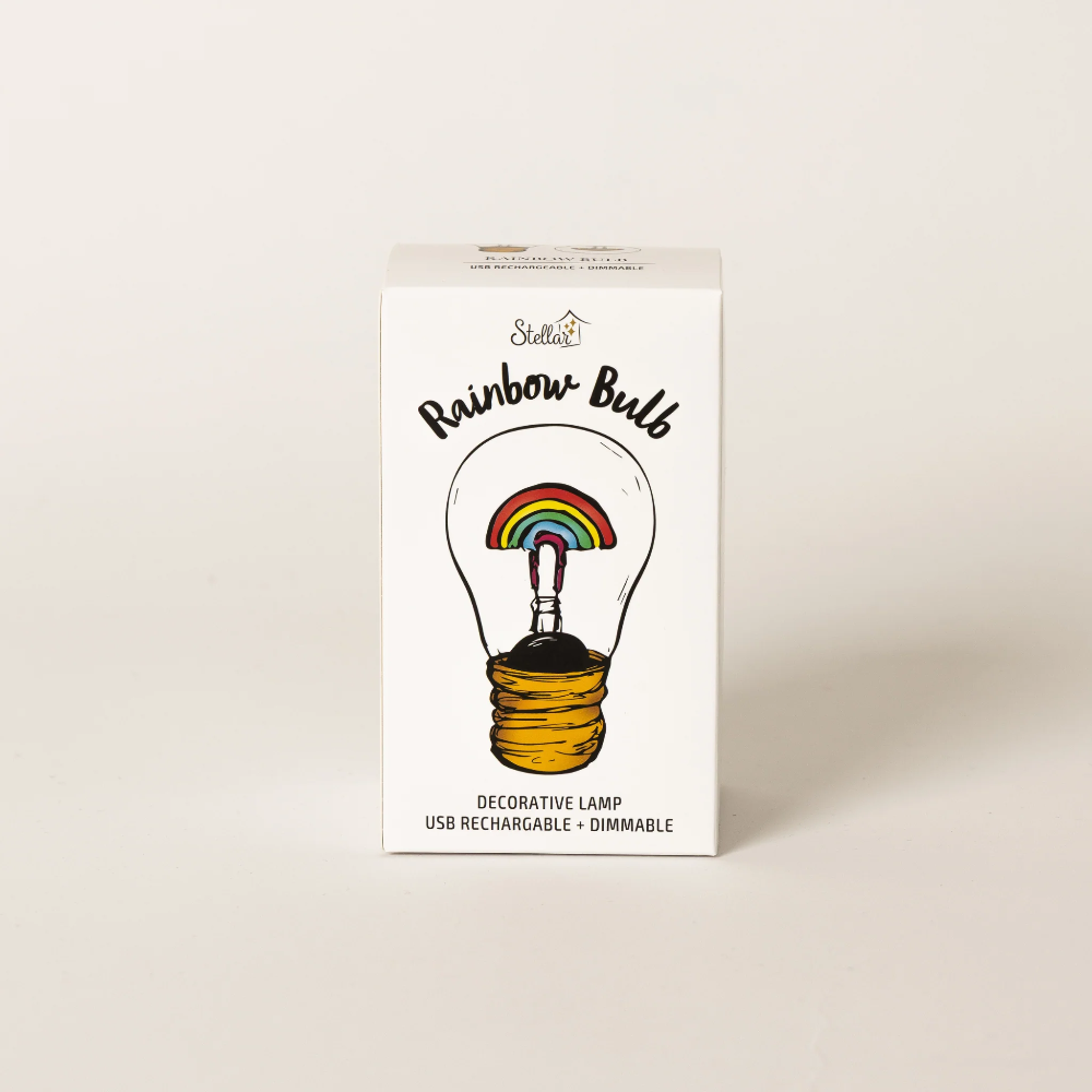 A white rectangular product box for a decorative lamp, featuring an illustration of a light bulb with a rainbow inside and the text 'Rainbow-Bulb' and 'Decorative Lamp USB Rechargeable + Dimmable.' The box is photographed on a clean, light beige background.