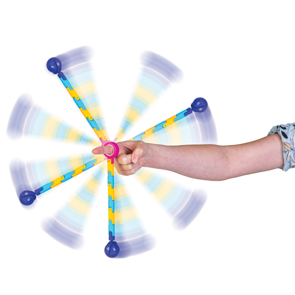A child's hand and arm extended to the right, holding the center of a spinning plastic toy with six arms. The toy has blue ball ends and yellow-and-blue striped arms, with motion-blur effects showing rotation on a plain white background.