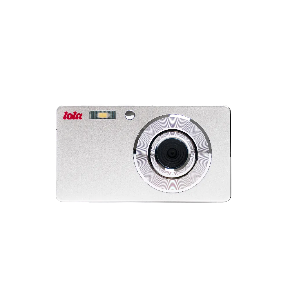 A compact silver digital camera with a red 'lola' logo on the top left, a glossy circular lens ring, and a small flash window, shown against a plain white background.
