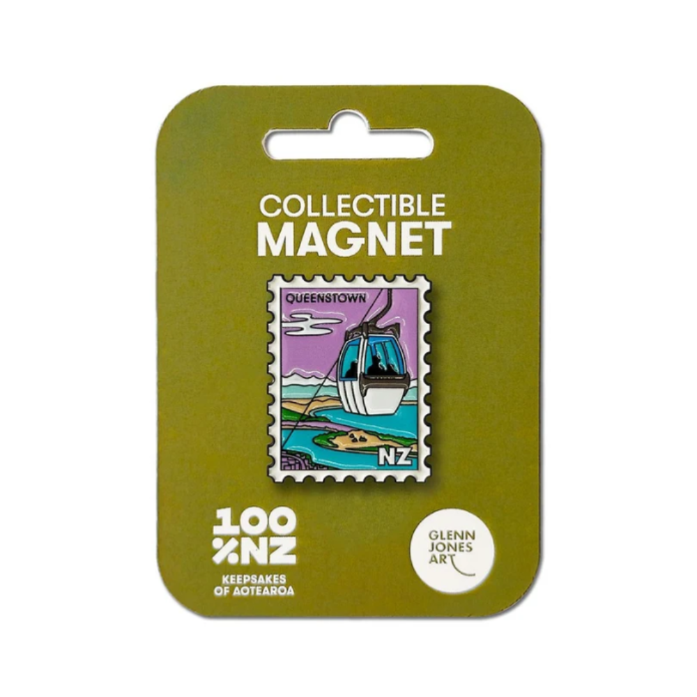 A collectible enamel magnet featuring Queenstown, New Zealand, mounted on its original olive green card packaging. The magnet depicts a cable car over a scenic landscape.