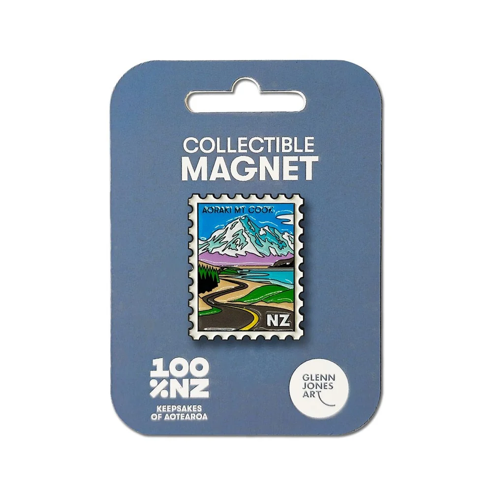A collectible magnet on a blue display card. The magnet is shaped like a vintage New Zealand postage stamp and features a landscape of mountains, a winding road, and lakes.