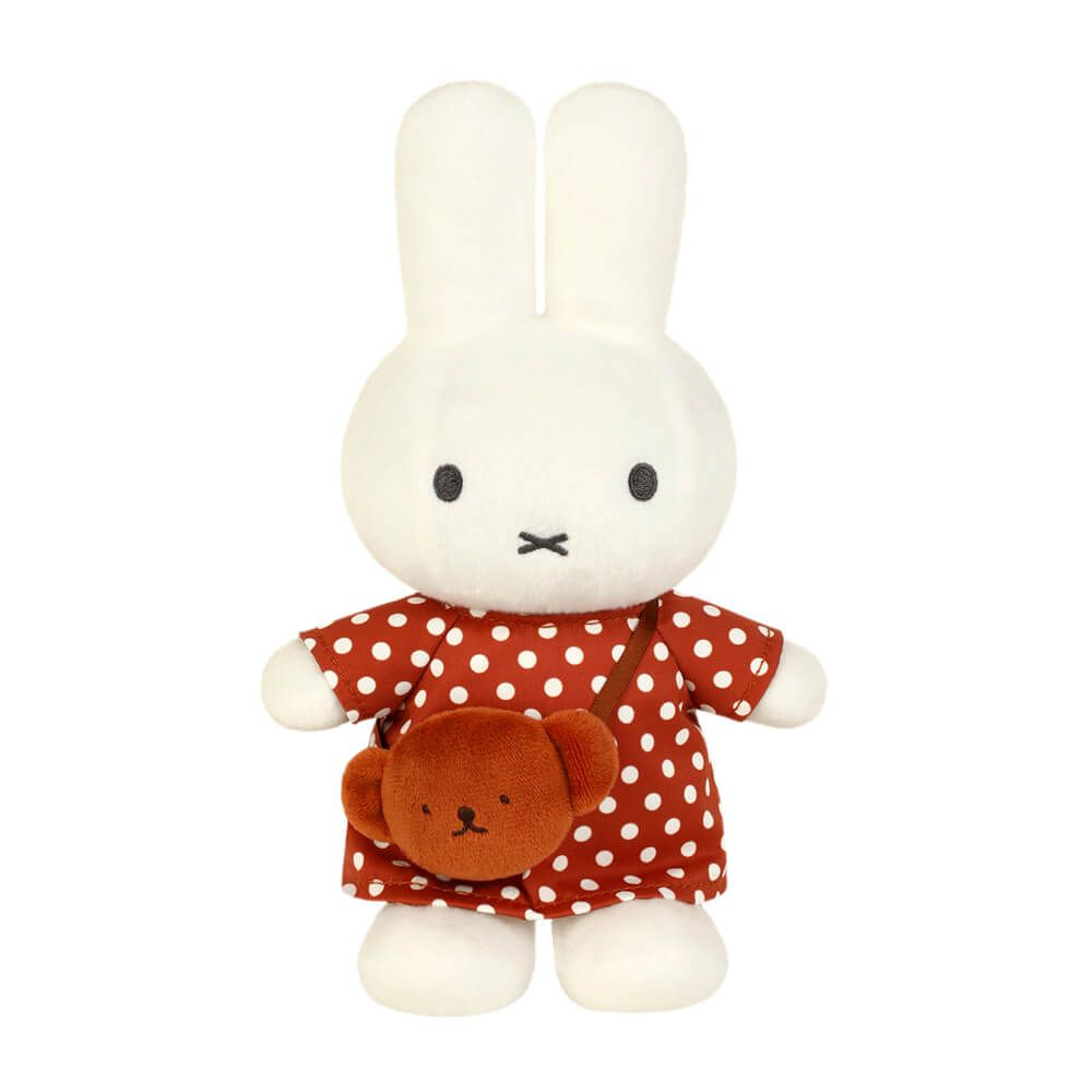 Plush toy rabbit in a red polka dot dress with a brown bag on a white background
