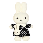 A plush rabbit toy with long white ears, black dot eyes, and a stitched black mouth, wearing a black dress with white polka dots and holding a small matching plush bunny bag.