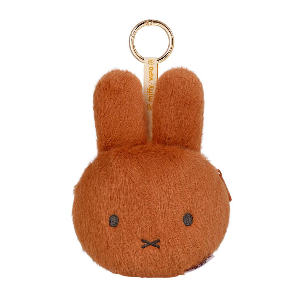 A round, orange-brown plush bunny keychain or coin purse with long ears, simple embroidered eyes and mouth, and a gold-tone key ring at the top. The tag reads 'miffy wip @'.
