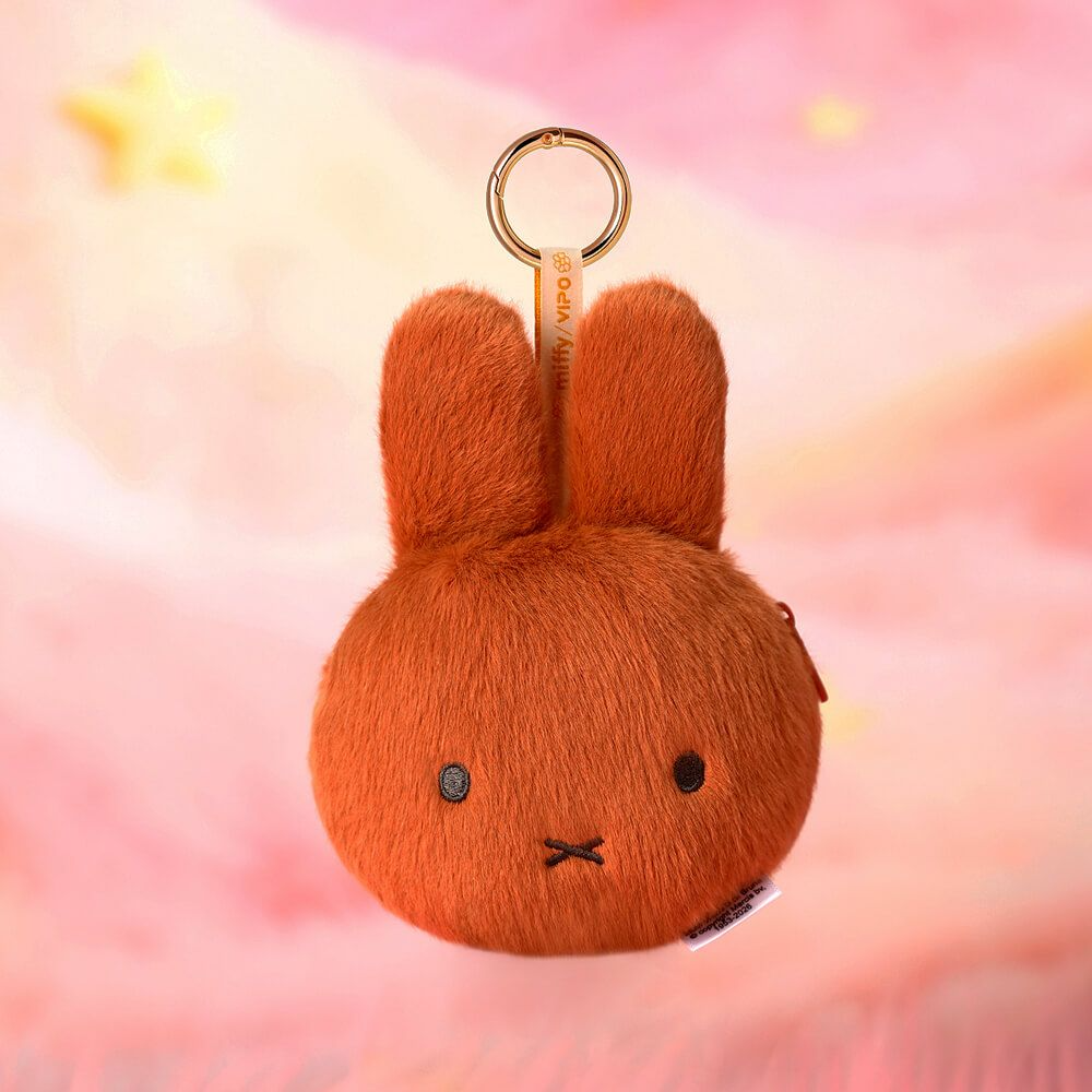 Brown plush bunny keychain on a soft pink background with star shapes