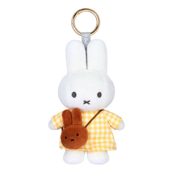 A plush Miffy keychain featuring a white bunny in a yellow and white checkered dress with a brown crossbody bag, attached to a gold split ring.