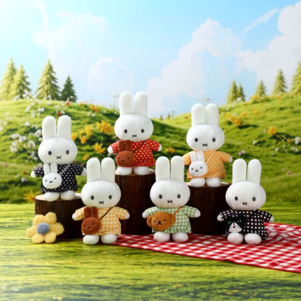 Six Miffy plush toys in different outfits and poses, arranged on wooden logs and a red-and-white checkered blanket against a painted grassy hill background.