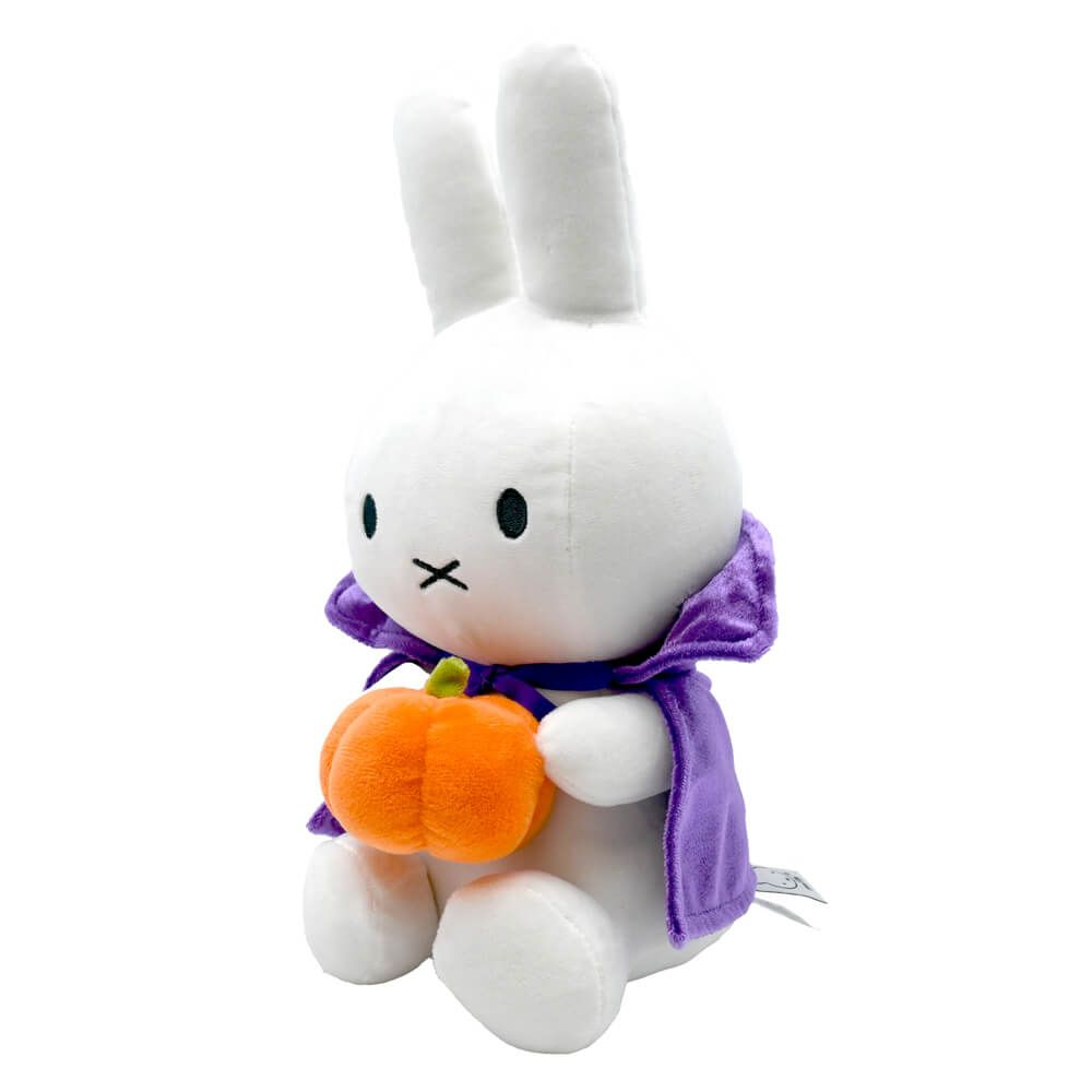 A white plush bunny toy wearing a purple cape and holding an orange pumpkin, photographed on a plain white background.
