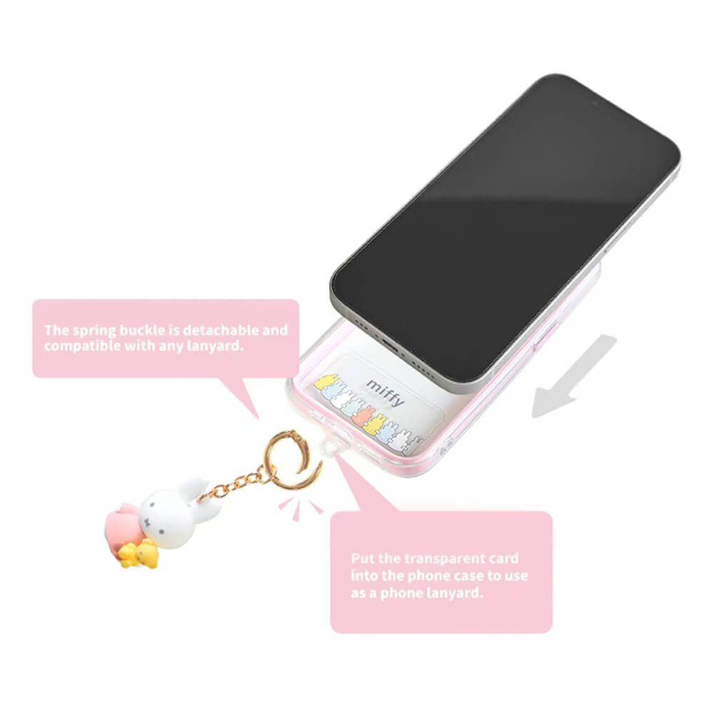 A clear phone case with a black phone inserted, shown on a white background with pink text callouts and a small cartoon keychain accessory. The case appears transparent with a black front panel and a gold-tone keychain ring.
