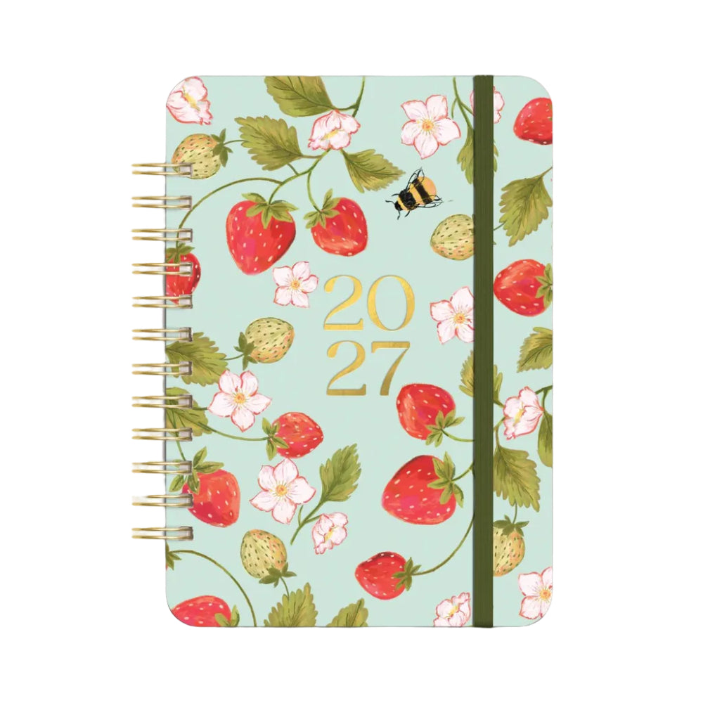 A spiral-bound 2027 planner with a light mint green cover decorated with a strawberry and flower pattern, gold '2027' text, and a black elastic closure band.