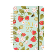 A spiral-bound 2027 planner with a light mint green cover decorated with a strawberry and flower pattern, gold '2027' text, and a black elastic closure band.