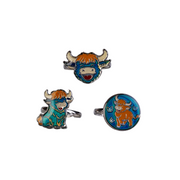 Three silver-tone bull-themed jewelry pieces on a plain white background: a bull head ring at the top, a seated bull charm at lower left, and a round bull face charm at lower right. The bull features orange hair, a blue face, and a teal body with white and red details.
