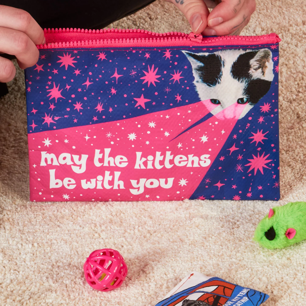 Person holding a pouch with a cat design and text on a carpeted floor.