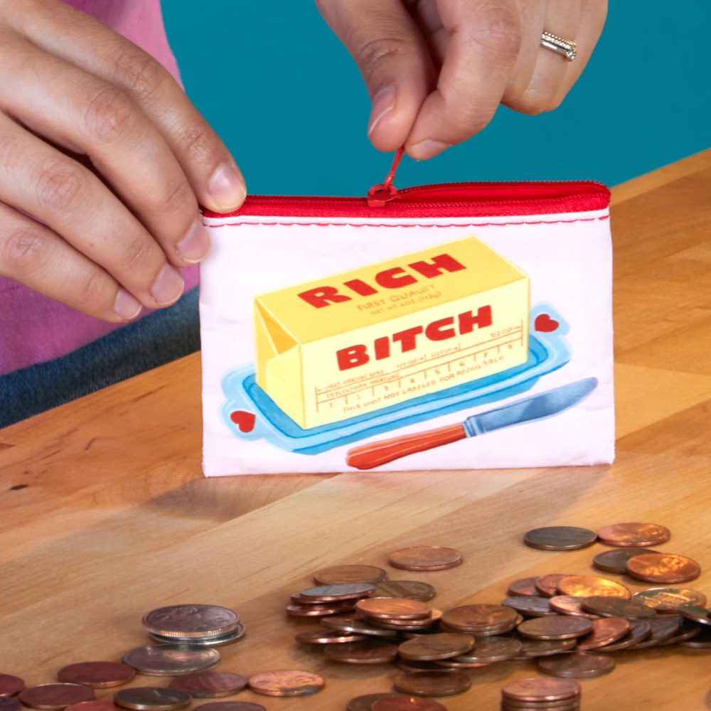 Person putting money into a small pouch with a graphic design on a wooden surface.