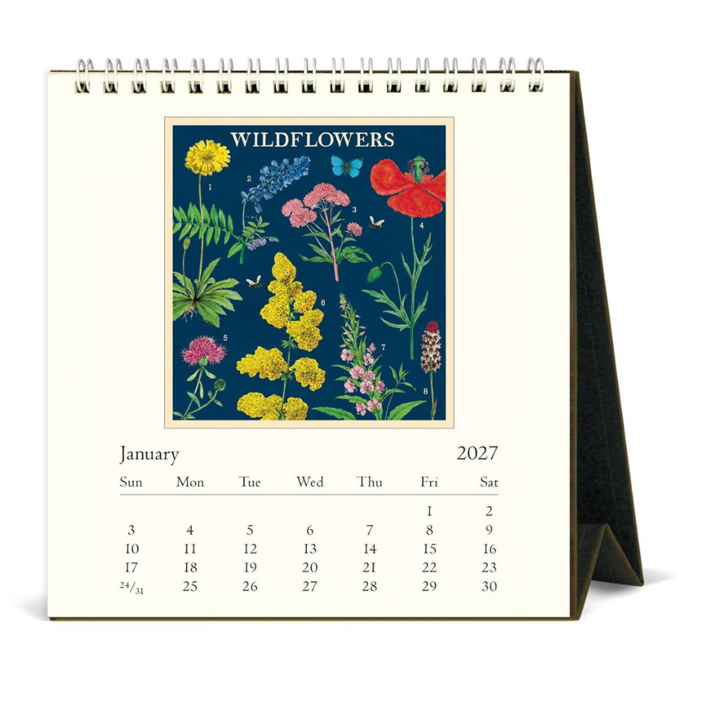 A spiral-bound desk calendar showing the January 2027 page, with a large central floral illustration titled 'WILDFLOWERS' on an off-white background.
