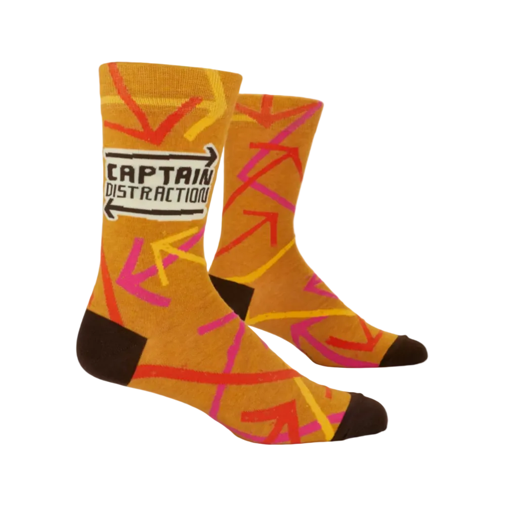 A pair of crew socks with a mustard yellow base, featuring a colorful abstract pattern of intersecting pink, red, and yellow lines, dark brown heels and toes, and a white label on the side that reads 'CAPTAIN DISTRACTION'.
