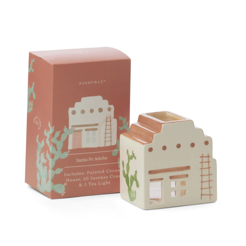 Paddywax Santa Fe Adobe house ceramic candle holder and its matching pink packaging box, featuring a cream-colored body with terracotta roof details and green cactus illustrations.