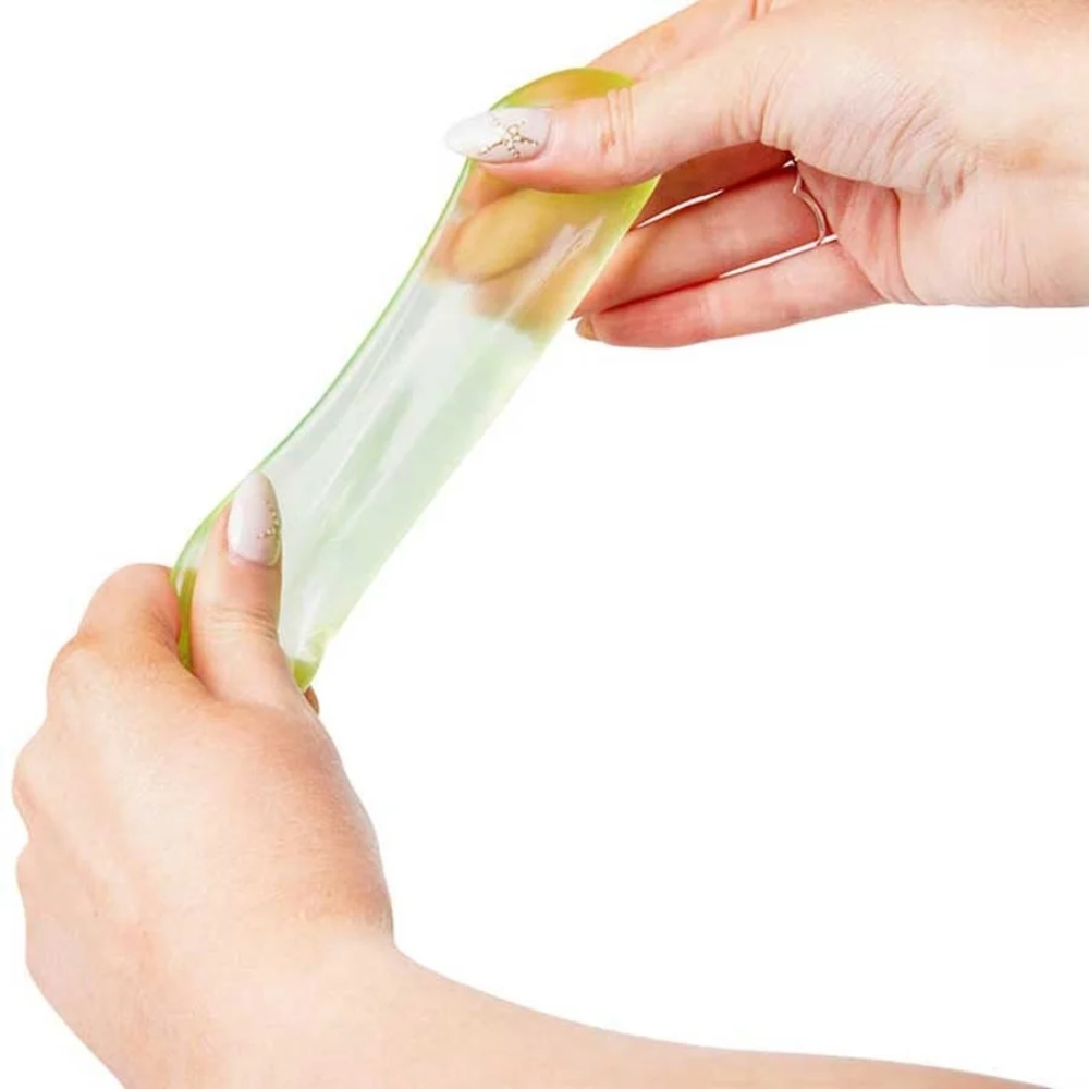 A close-up of a person's hands stretching a translucent light green silicone gel pad against a solid white background.