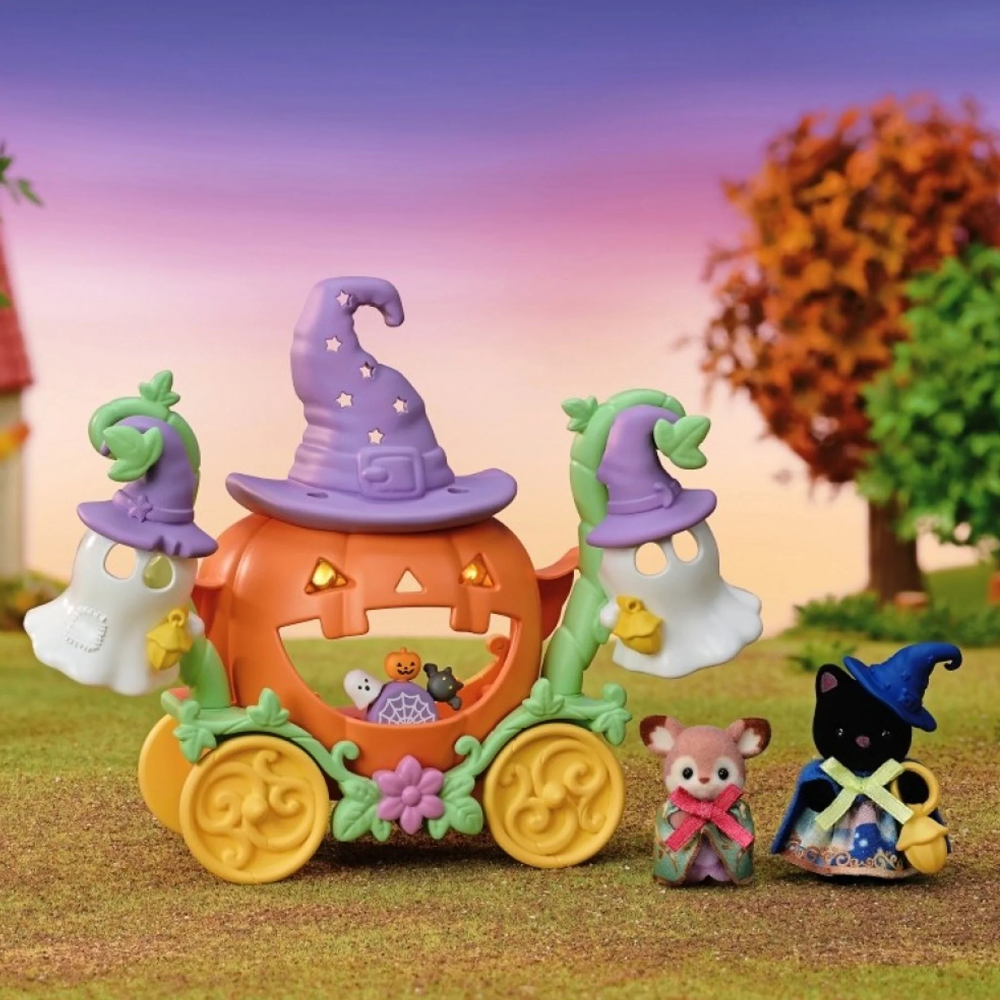 Halloween-themed toy set featuring a jack-o'-lantern carriage with purple witch hats, ghost figures, a small cat figurine, and a black cat character, displayed in a miniature outdoor scene with grass, trees, and a sunset sky.