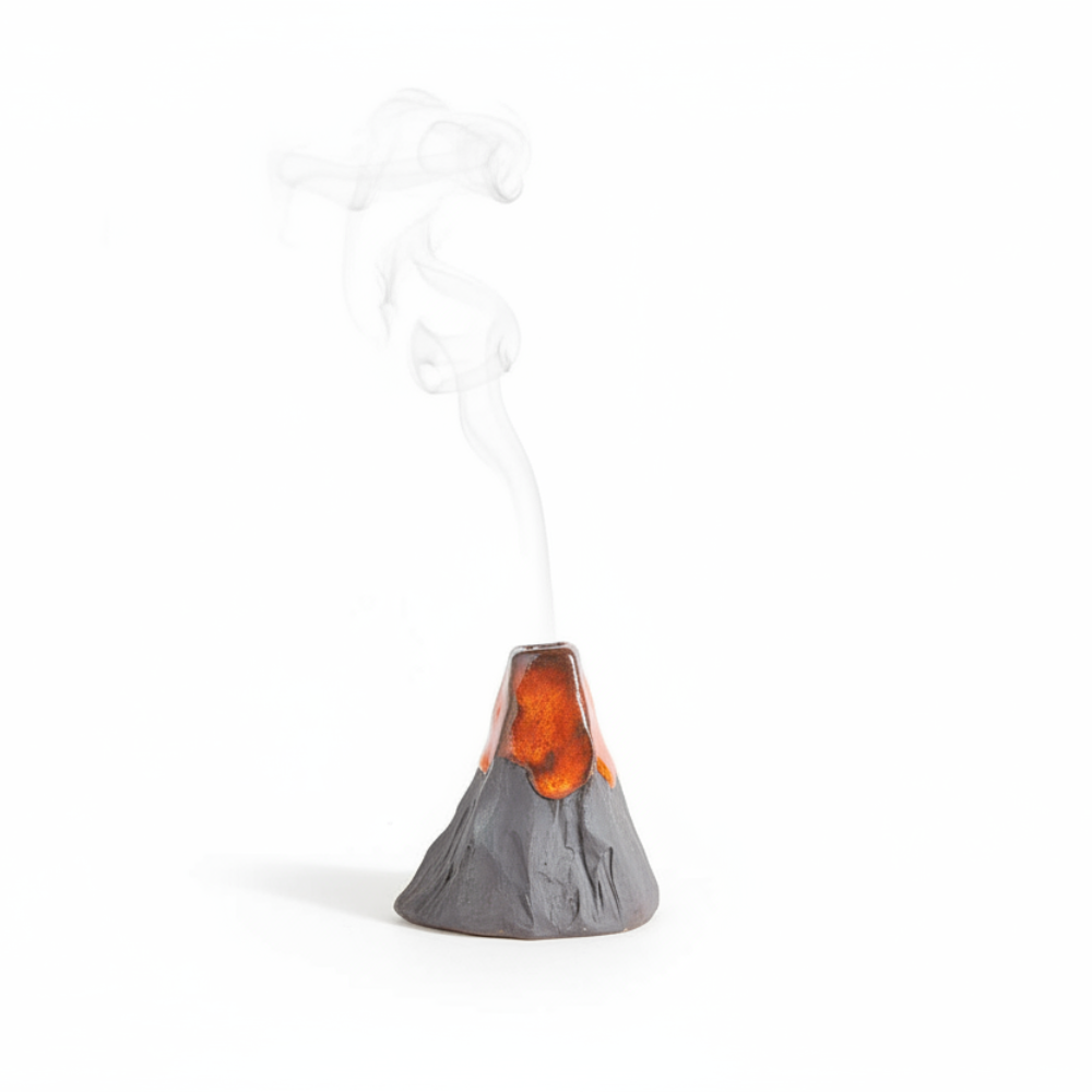 A miniature gray volcano figurine with glowing orange lava and white smoke rising from its top, set against a dark gray background.
