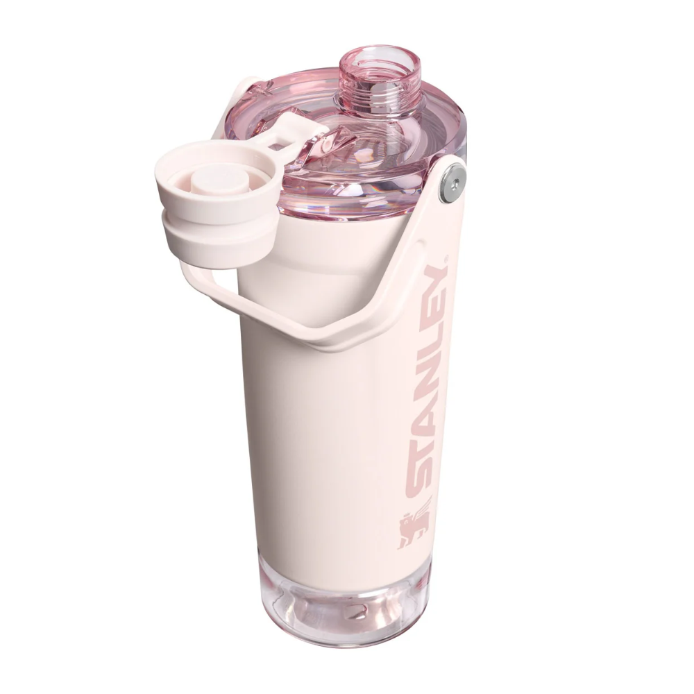 A Stanley water bottle in pale pink with a translucent pink lid and a flip-up straw spout, shown on a plain white background.