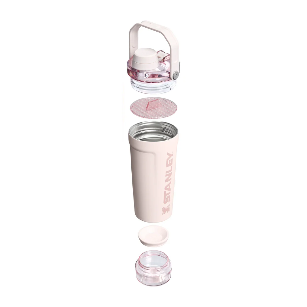 A light pink Stanley travel tumbler shown in an exploded disassembled view on a solid white background, displaying its separate lid, handle, inner liner, and base.