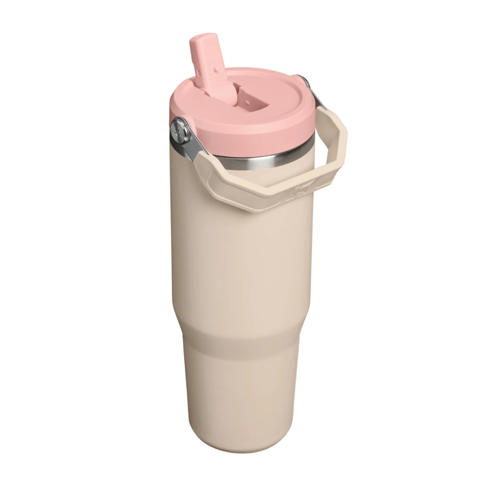 A tall insulated travel tumbler in a warm cream-beige color, featuring a light pink lid with a flip-up straw spout and a beige carrying handle, isolated on a white background.