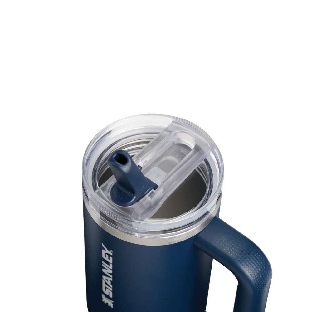 Stanley insulated tumbler with a navy blue body, clear lid, and dark blue handle on a white background.
