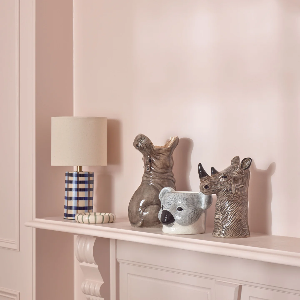 Decorative items including a lamp, vases, and a bowl on a shelf against a pink wall.