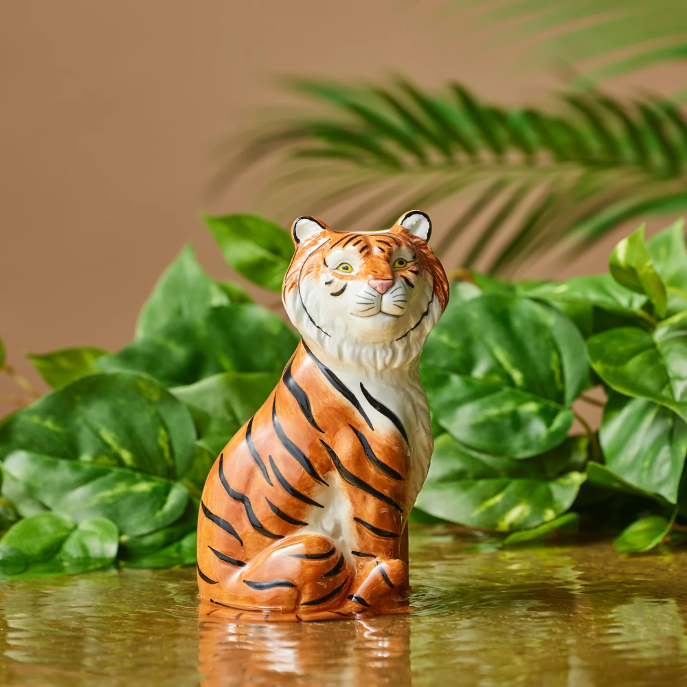 Tiger figurine in front of green leaves