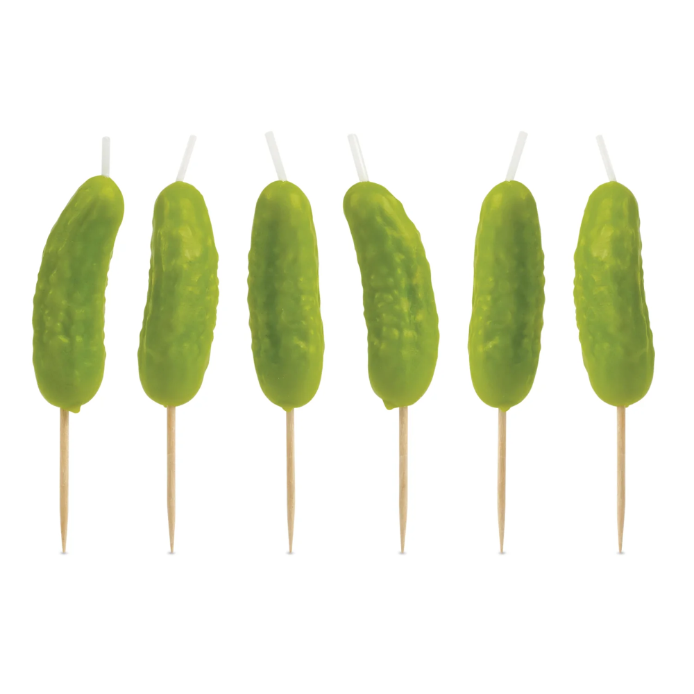 Six green pickle-shaped candles on wooden sticks against a white background