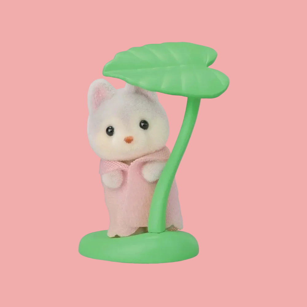 A small plush toy cat figurine standing under a green leaf-shaped lamp or umbrella on a round base, wearing a pink dress, against a plain white background.