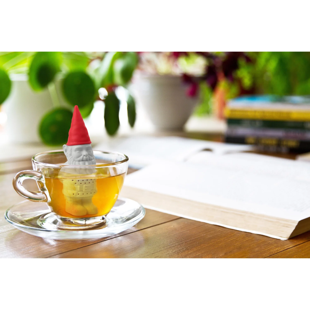 Tea cup with a gnome-shaped tea infuser on a wooden table with a blurred background