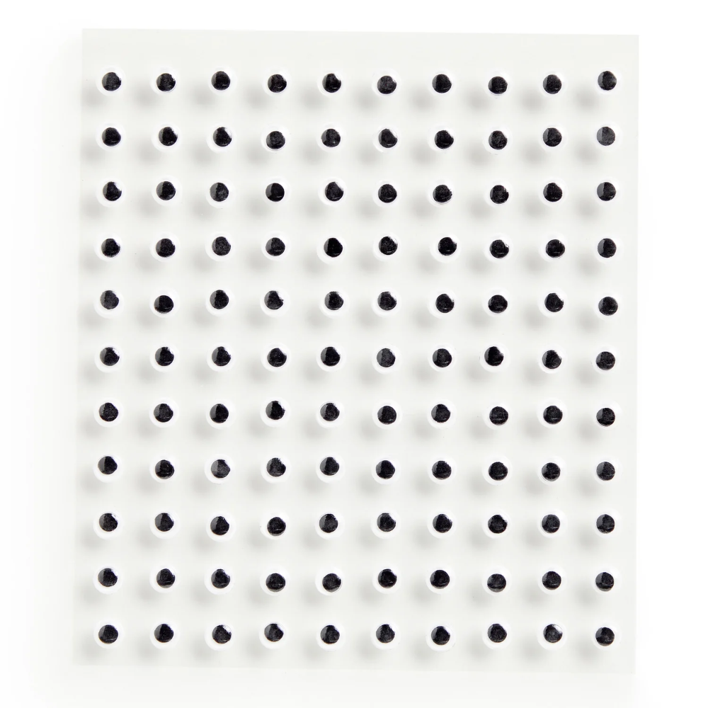 A square white textured panel featuring a uniform grid of small, evenly spaced black circular dots, photographed against a clean white background.