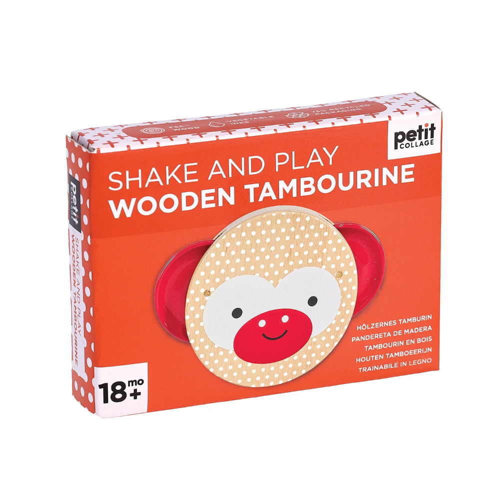 A boxed toy product labeled 'petit COLLAGE Shake and Play Wooden Tambourine' on a plain white background. The package is predominantly orange with white polka dots, white text, and a photo of the round wooden tambourine with red side handles and a beige monkey face on the front.