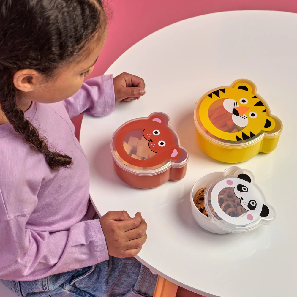 Child with animal-themed lunch boxes on a white table