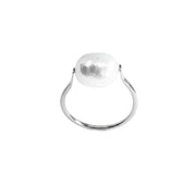 A minimalist silver ring featuring a large, irregularly shaped, hammered white stone in a prong setting, shown against a plain white background.